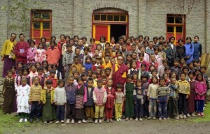 In this photo taken June 1999 and released by Tsering Woeser on July 13, 2015, Tibetan lama Tenzin Delek Rinpoche, center in red robes, poses for photo with orphans at a school in Nyagqu County, also known as Yajiang County in the Garze Tibetan Autonomous Prefecture in southwestern China's Sichuan province. Relatives of Tenzin Delek Rinpoche were informed Sunday, July 12, 2015 that he has died in prison 13 years into serving a sentence for what human rights groups say were false charges that he was involved in a bombing in a public park. He was 65. (Tsering Woeser via AP)