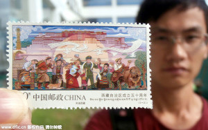 A Chinese stamp collector shows a stamp issued to mark the 50th anniversary for the establishment of Tibet autonomous region at a China Post Office in Suzhou city, East China's Jiangsu province. (Photo / IC)
